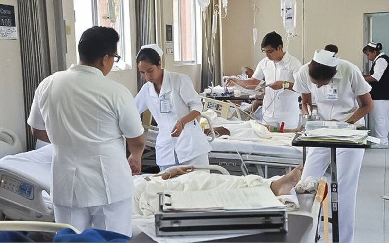 Personal médico atiende a un paciente en una cama de hospital.