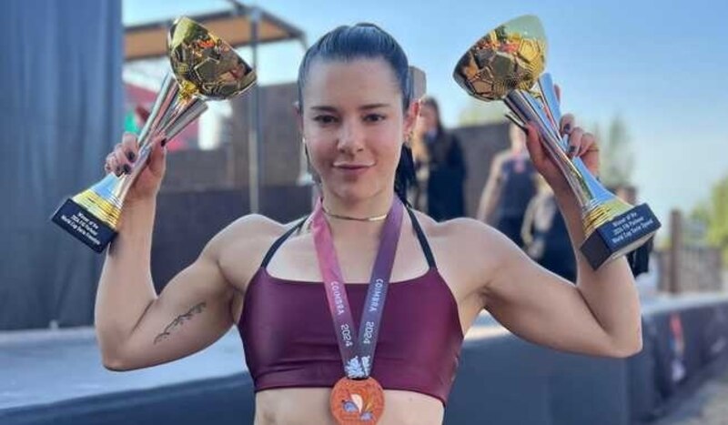 Mujer deportista con dos trofeos en sus manos.