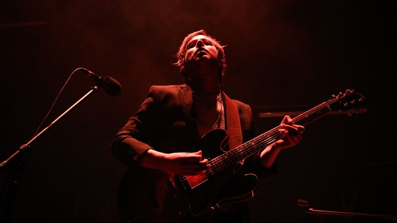 El músico está tocando la guitarra en un concierto.