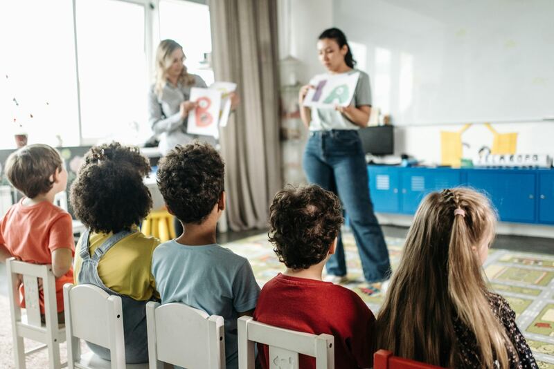 Un salón de clases con maestras que les enseñan a los niños
