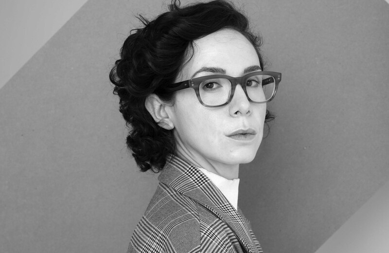 Retrato en blanco y negro de una mujer con gafas y traje de chaqueta.