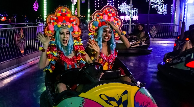 Mujeres jóvenes conduciendo un coche de choque en un parque de atracciones.