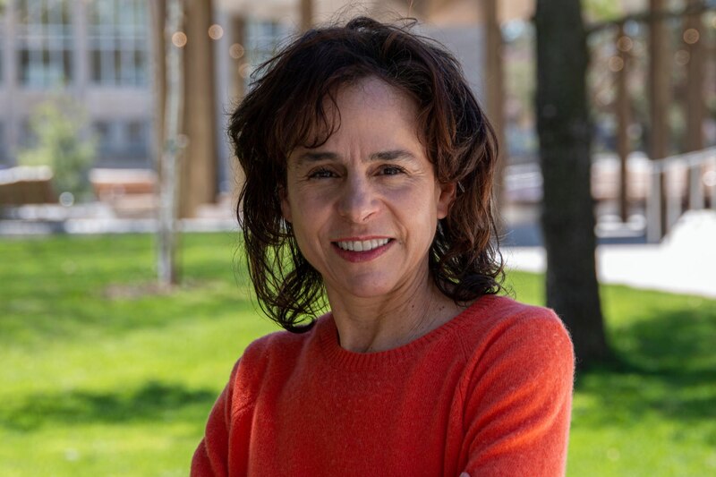 Mujer sonriente con pelo castaño y suéter rojo