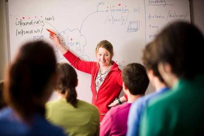 Profesora dando clase en la pizarra