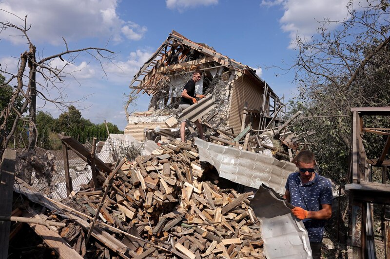 Dos hombres limpian los escombros de una casa destruida