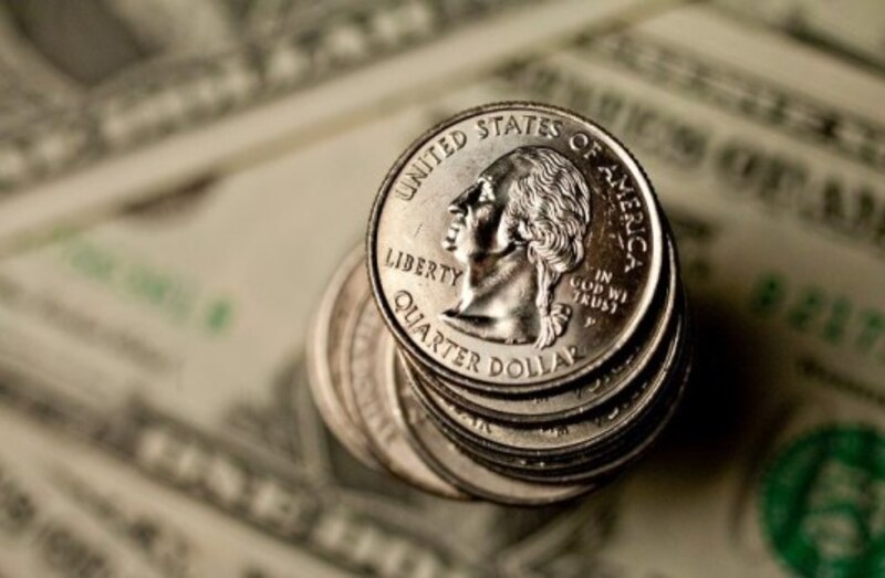 Monedas de 25 centavos apiladas sobre billetes de 100 dólares