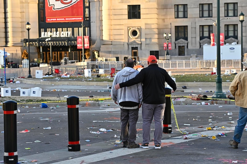 Dos hombres abrazados miran la destrucción en las calles de Kansas City tras la celebración del Super Bowl.