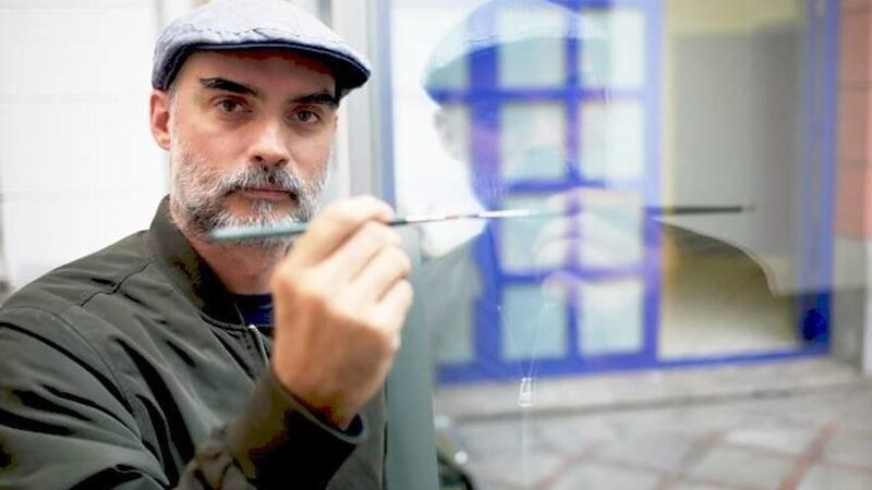 Un artista pinta un mural en una ventana