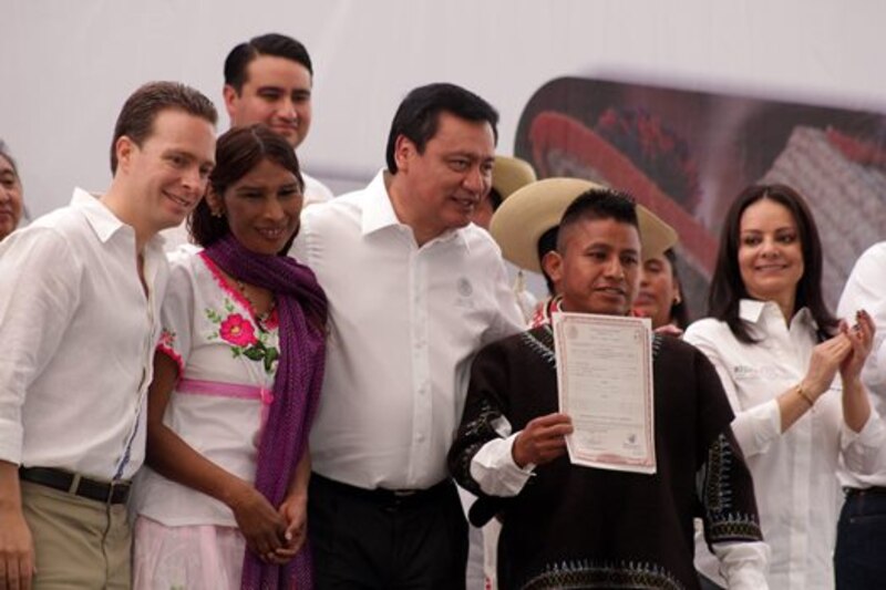El presidente ecuatoriano Rafael Correa entrega un título de propiedad de vivienda a un joven indígena