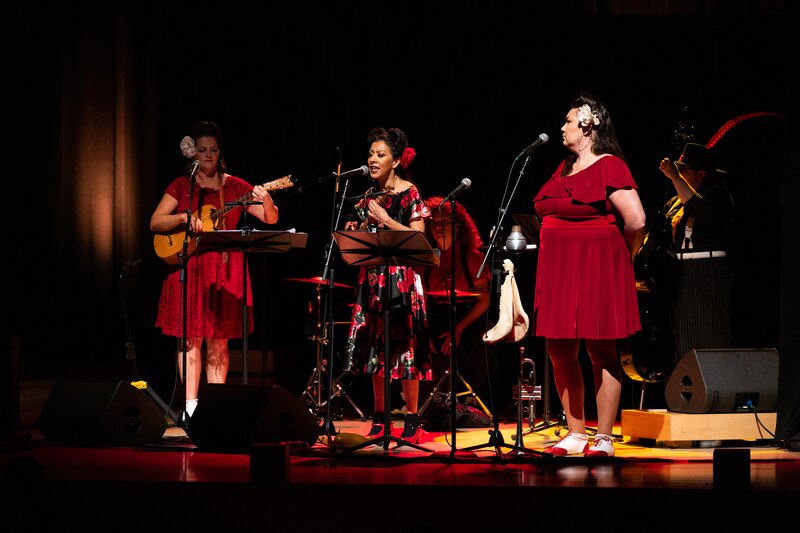 Trío de mujeres cantando en un escenario