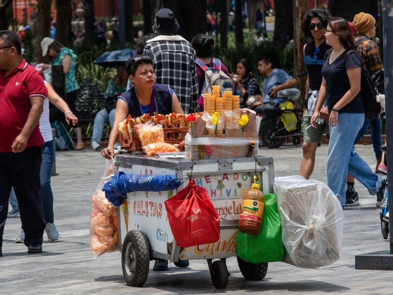 Mujer vendiendo comida en un carrito en la calle