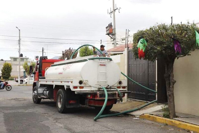 Un camión de agua abastece a una casa en una calle de la Ciudad de México.