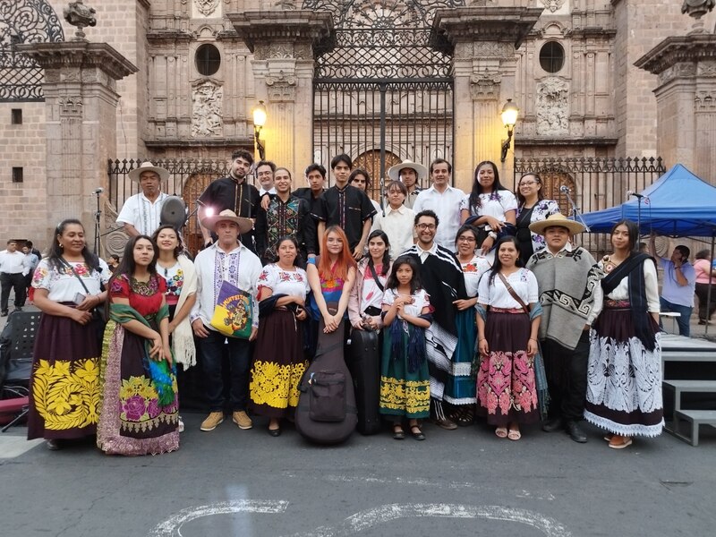 Grupo de personas en ropa tradicional mexicana posando frente a una catedral.