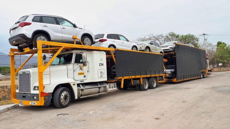 Un camión de plataforma con varios coches encima