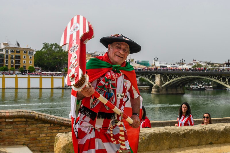Un hombre vestido con un traje tradicional español sostiene una bandera del Real Betis Balompié.