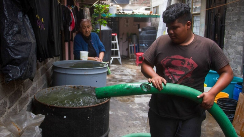 Niño mexicano acarreando agua con una manguera