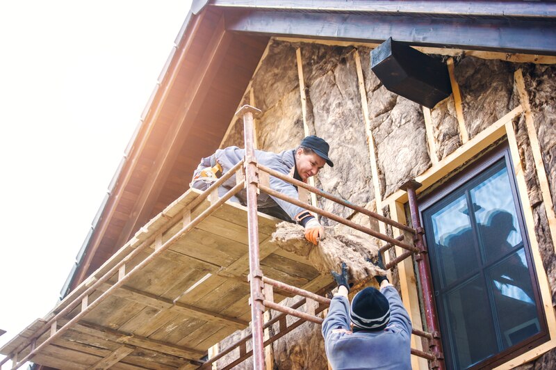 Dos trabajadores instalando aislamiento térmico en una fachada de una casa