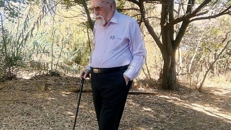 Un anciano camina con un bastón en un parque
