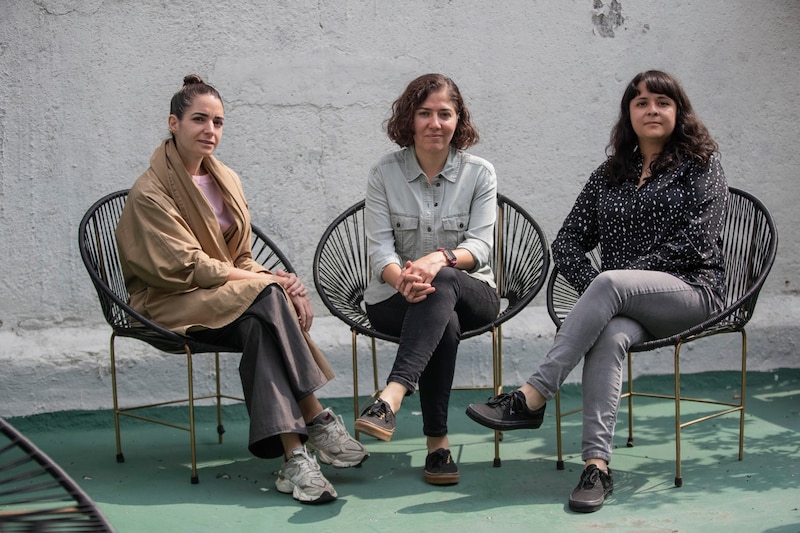 Tres mujeres sentadas en sillas de mimbre.