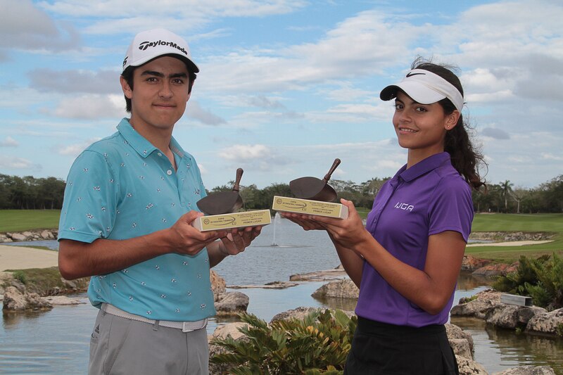 Dos jóvenes golfistas sostienen sus trofeos en un campo de golf.