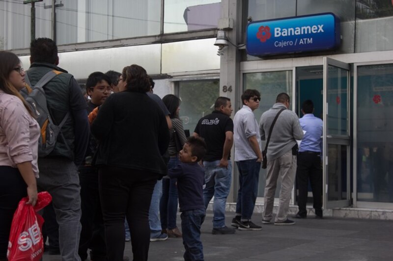 Larga fila de personas esperando para usar el cajero automático del banco Banamex.