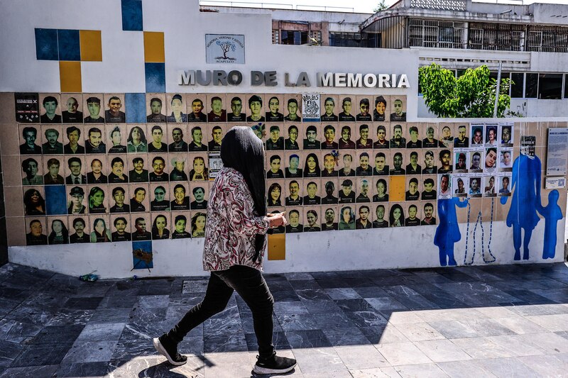 Title: Mujeres caminando frente al Muro de la Memoria en Acapulco