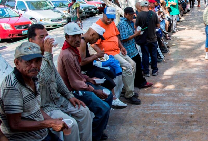 Personas sin hogar esperan en fila para recibir comida