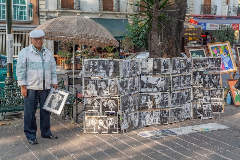 Un anciano vende fotos antiguas en la calle.