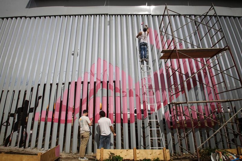 Un grupo de artistas pinta un mural en la frontera entre México y Estados Unidos.