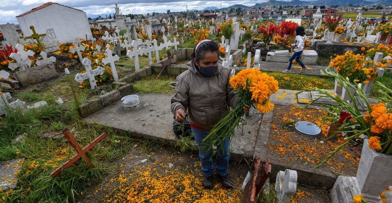 Mujer arreglando flores en un cementerio