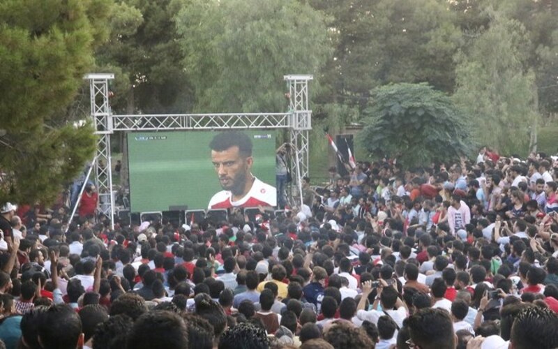 Multitud de aficionados al fútbol viendo un partido en una pantalla gigante