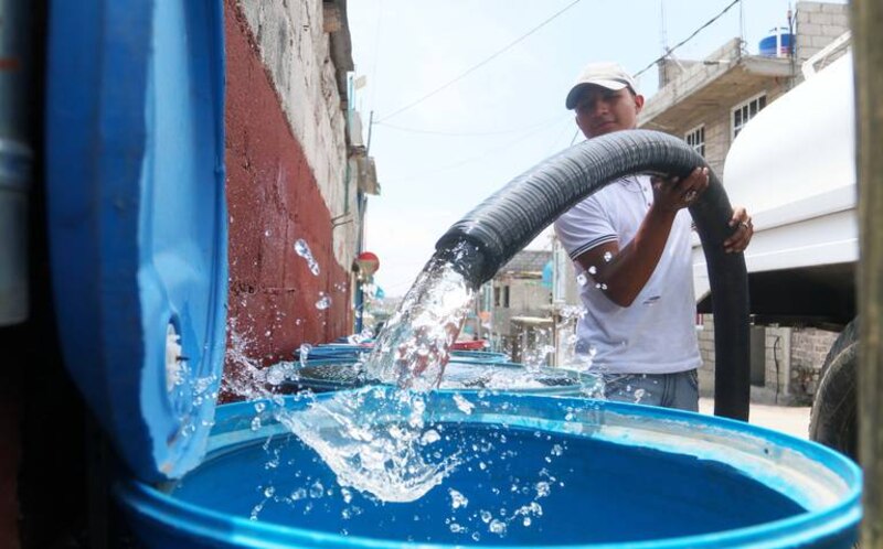 Un hombre llena un recipiente con agua de un camión cisterna.