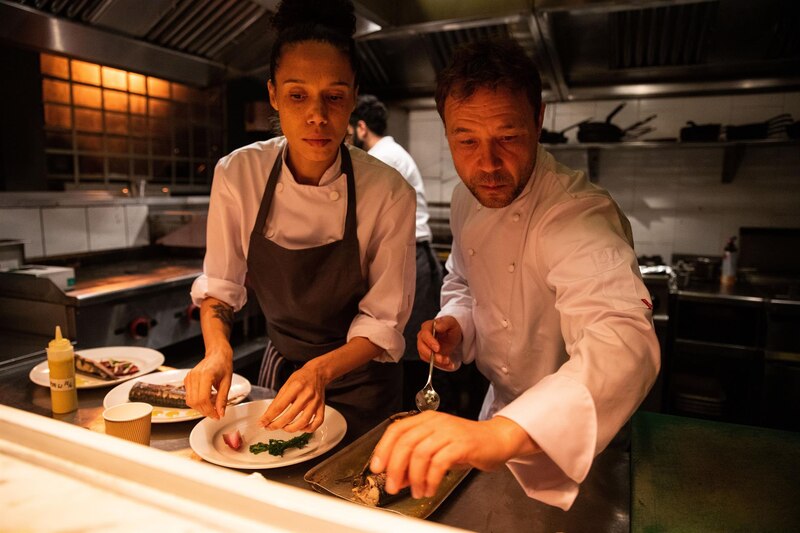 Chefs preparando un plato en la cocina de un restaurante.