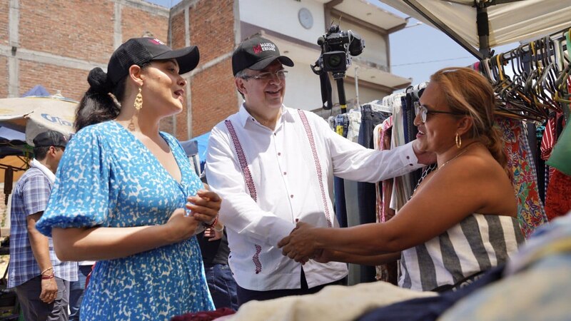 El candidato a la presidencia saluda a una mujer en un mercado.