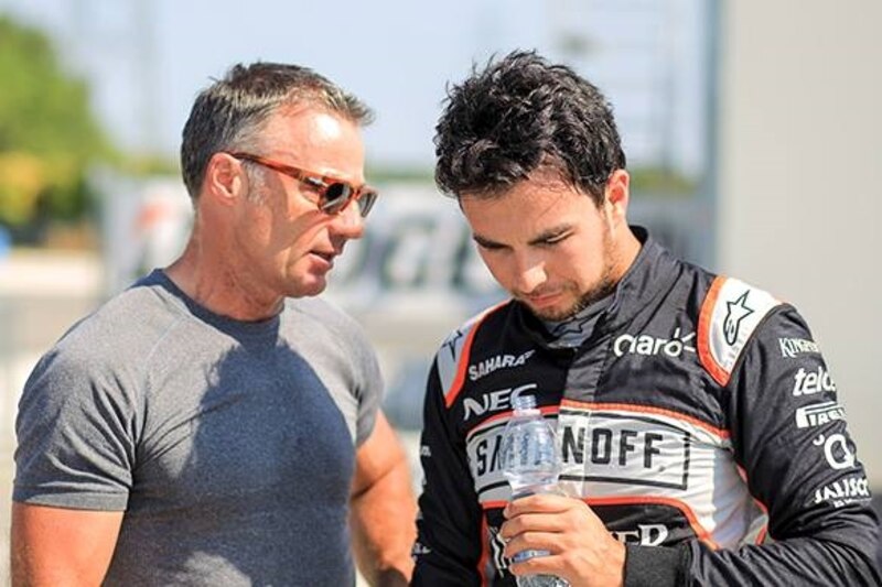 El piloto de automovilismo español, Fernando Alonso, habla con su entrenador.
