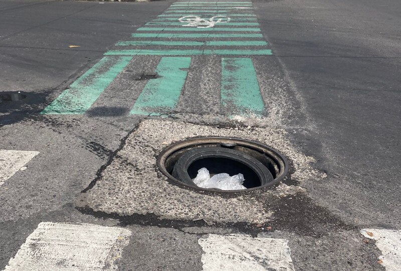 Bache en la calle con tapa de alcantarilla