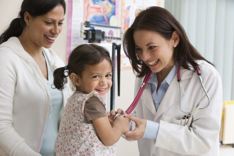 La doctora revisa a la niña mientras la madre mira.