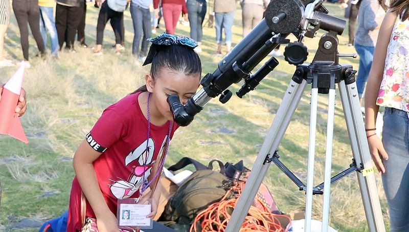 Niña mirando por un telescopio