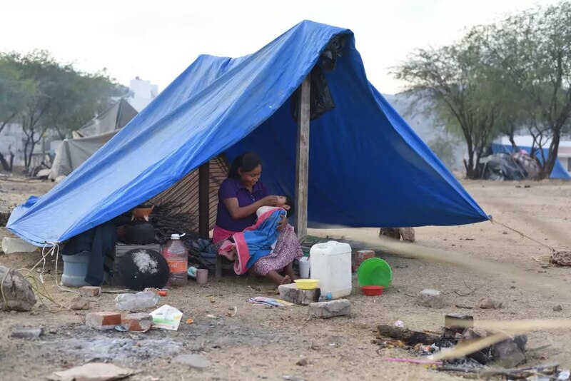 Madre e hijo migrantes descansan en un campamento improvisado