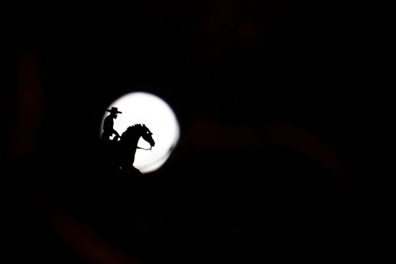 Silueta de un vaquero a caballo bajo la luna llena