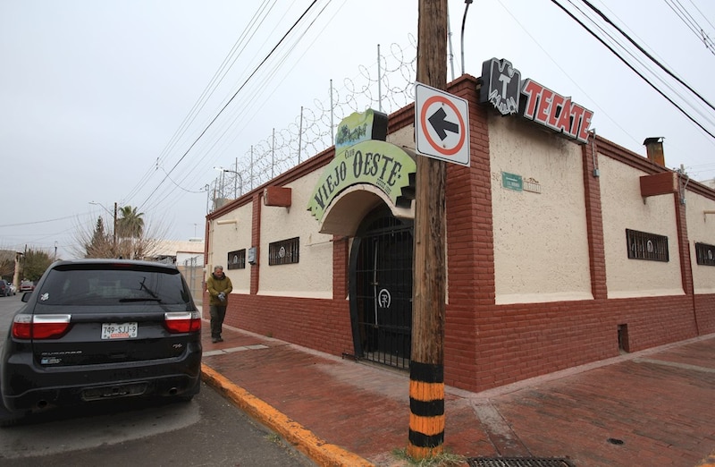 Un hombre camina por la acera junto a un edificio con un cartel que dice "Viejo Oeste".