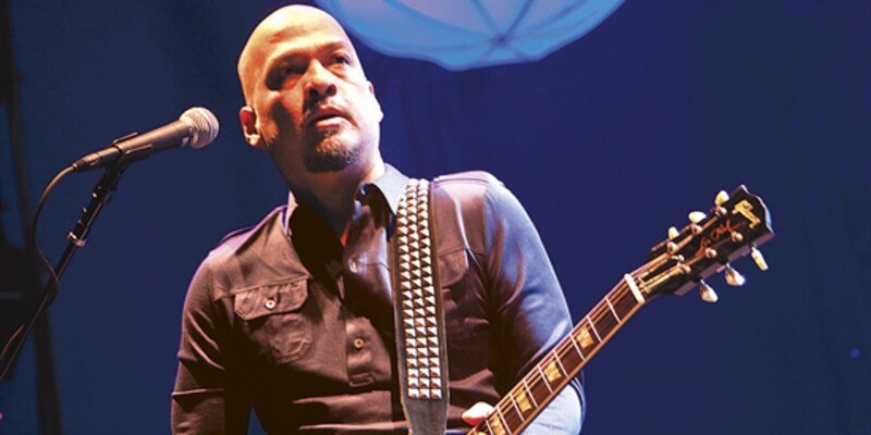 El músico Lenny Kravitz tocando la guitarra en un concierto.
