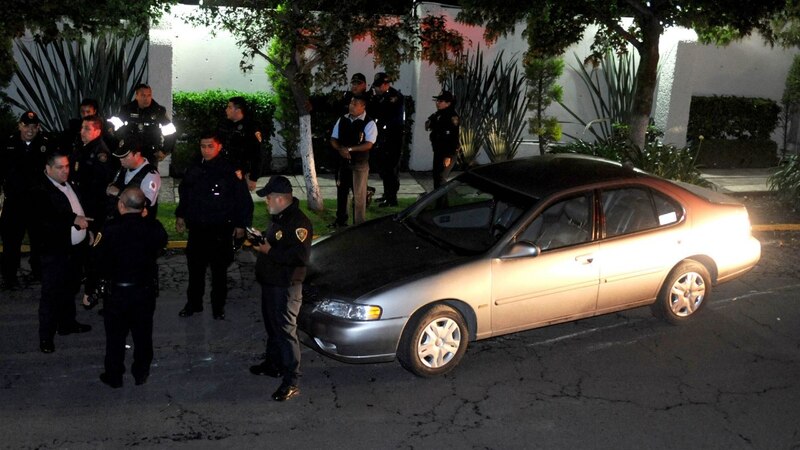 Policías rodean un auto gris en la noche