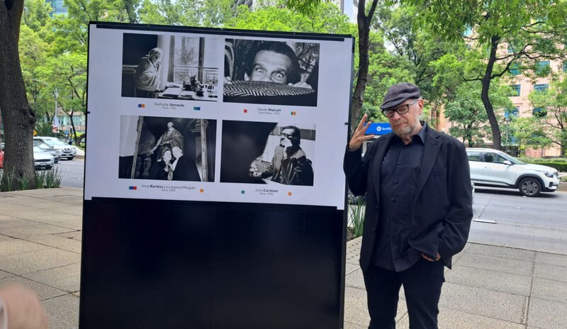 El escritor Carlos Monsiváis observa los retratos de otros escritores en una exposición al aire libre.