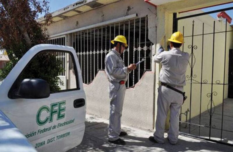Dos trabajadores de la CFE realizan trabajos de mantenimiento en una casa