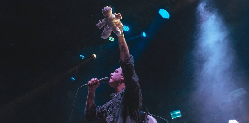 Cantante sosteniendo un peluche en un concierto