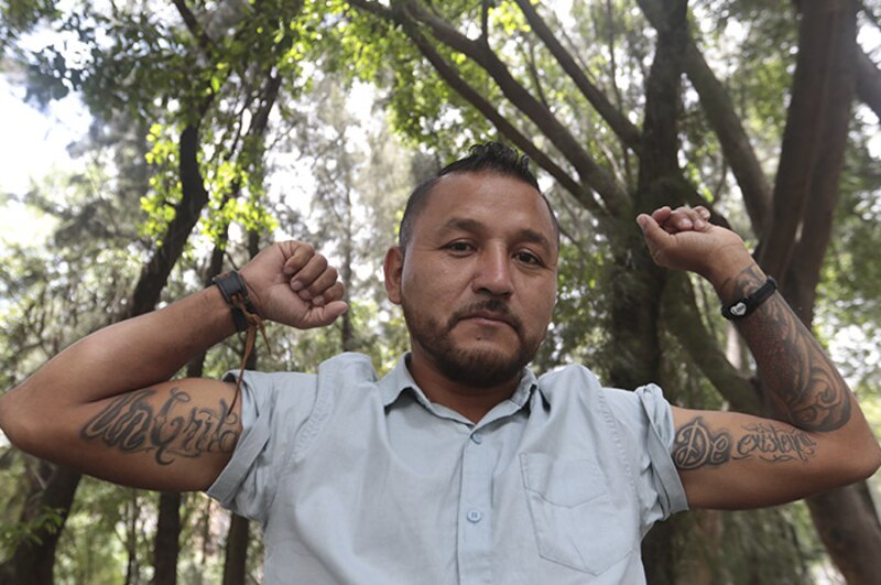 Un hombre muestra sus tatuajes.
