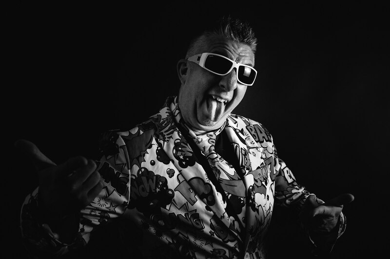 Un hombre con un traje llamativo y gafas de sol haciendo un gesto con los pulgares hacia arriba.
