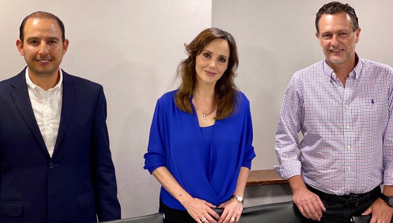 La imagen muestra a tres personas sonrientes, vestidas con ropa formal, en una oficina.