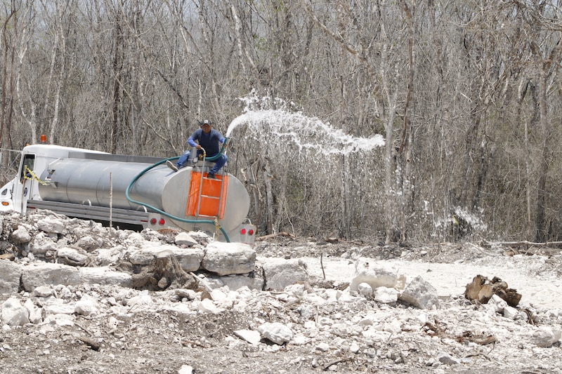 Un camión cisterna vierte agua en un camino de terracería.